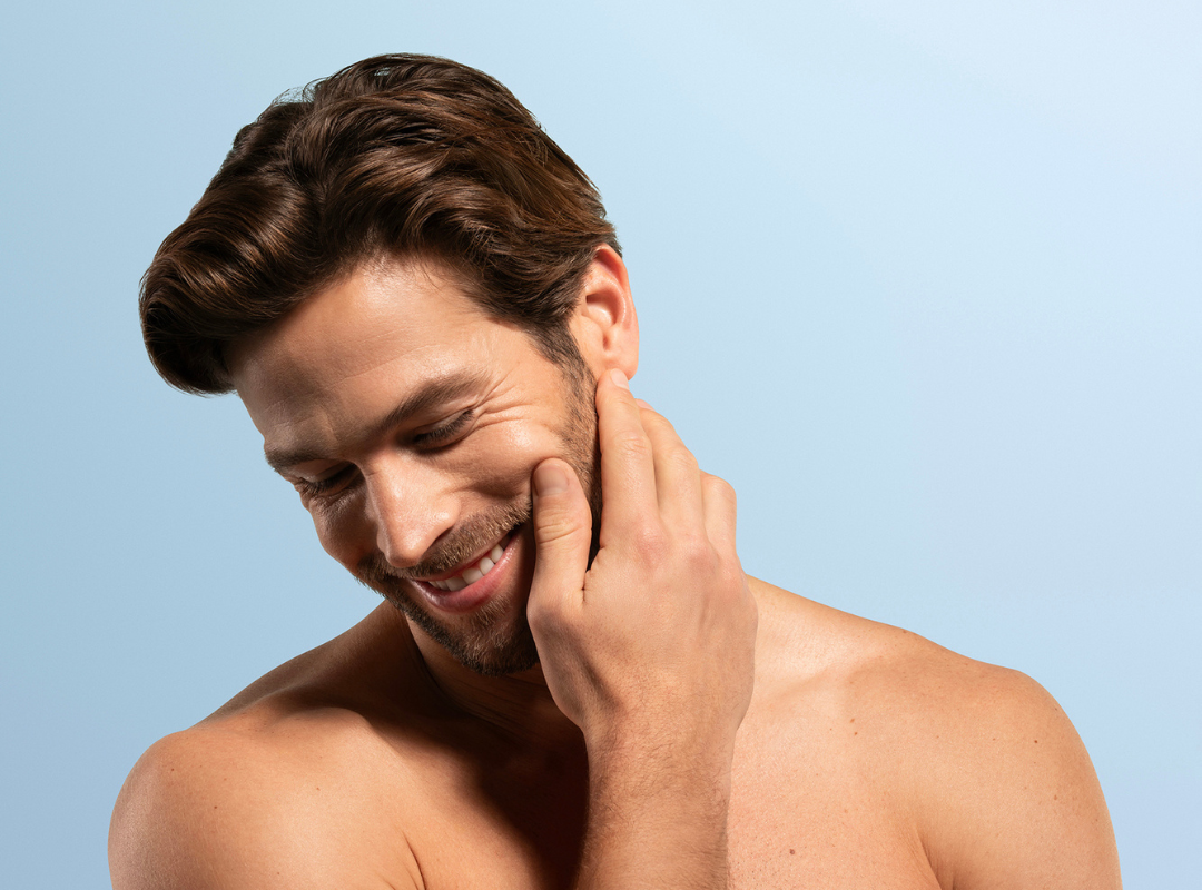 Men smiling infront of light blue background