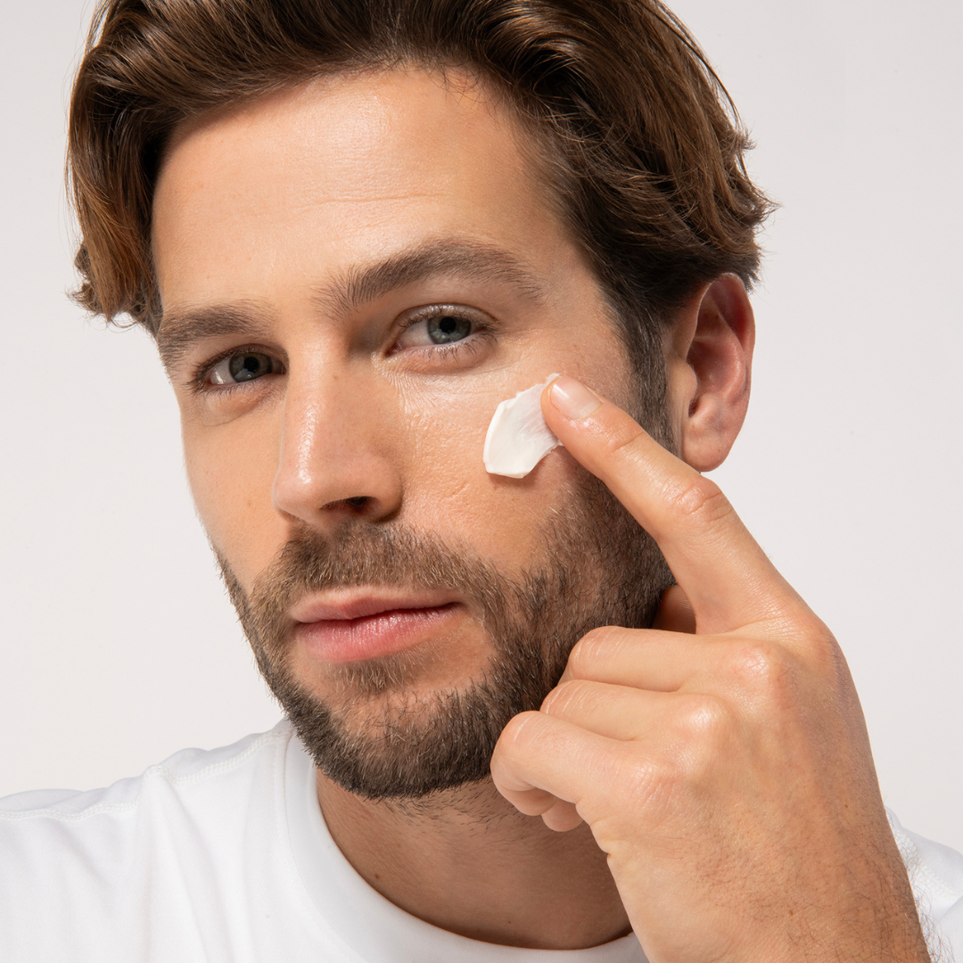 Aruba Aloe Man applying cream to his face with a white background